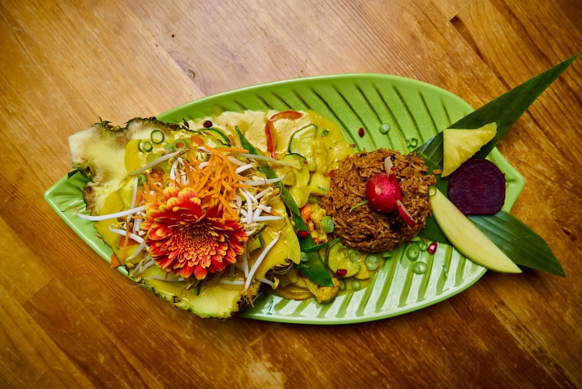 Kreolische Platte auf Bananenblatt mit Kochbananen-Röllchen und Salat