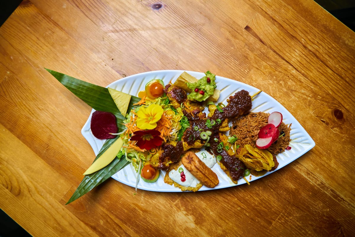 Platte mit Blüten, Kochbananen und gegrilltem Fleisch