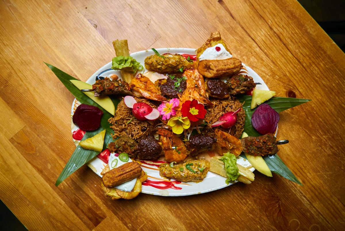 Karibische Platte mit Kochbananen, Salat und Rote-Bete-Chips auf Holztisch