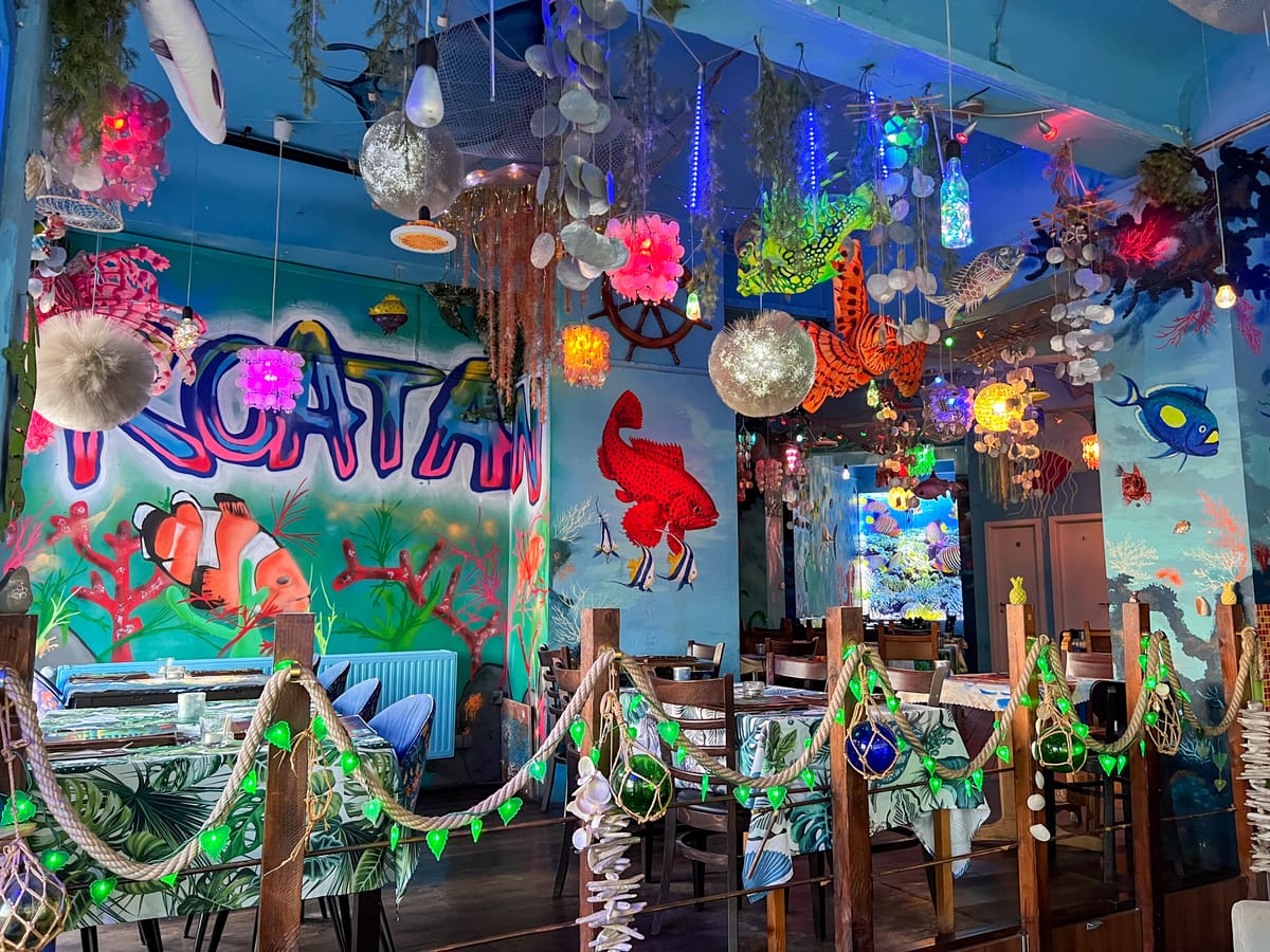 Der Saal: gemaltes Riff mit Flamingos und Muscheln an der Wand, bunte Lichterketten unter der Decke