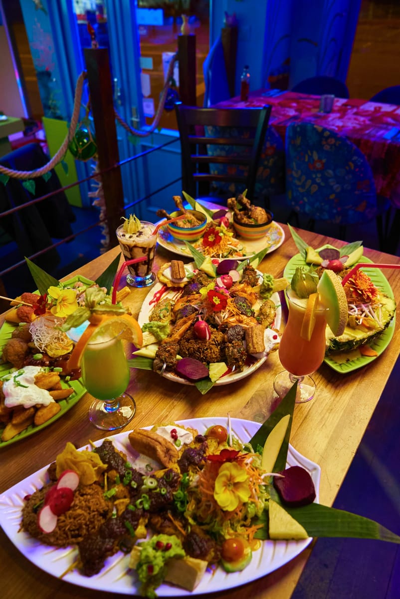 Ein gedeckter Tisch mit mehreren karibischen Platten und Cocktails